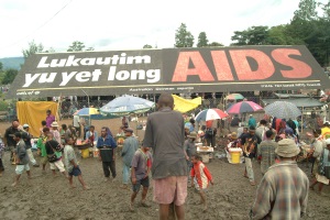 Picture of a billboard at a busy market in PNG that reads "Lukautim yu yet long AIDS"